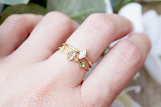 Gold ring with gemstones on a hand against a blurred natural background