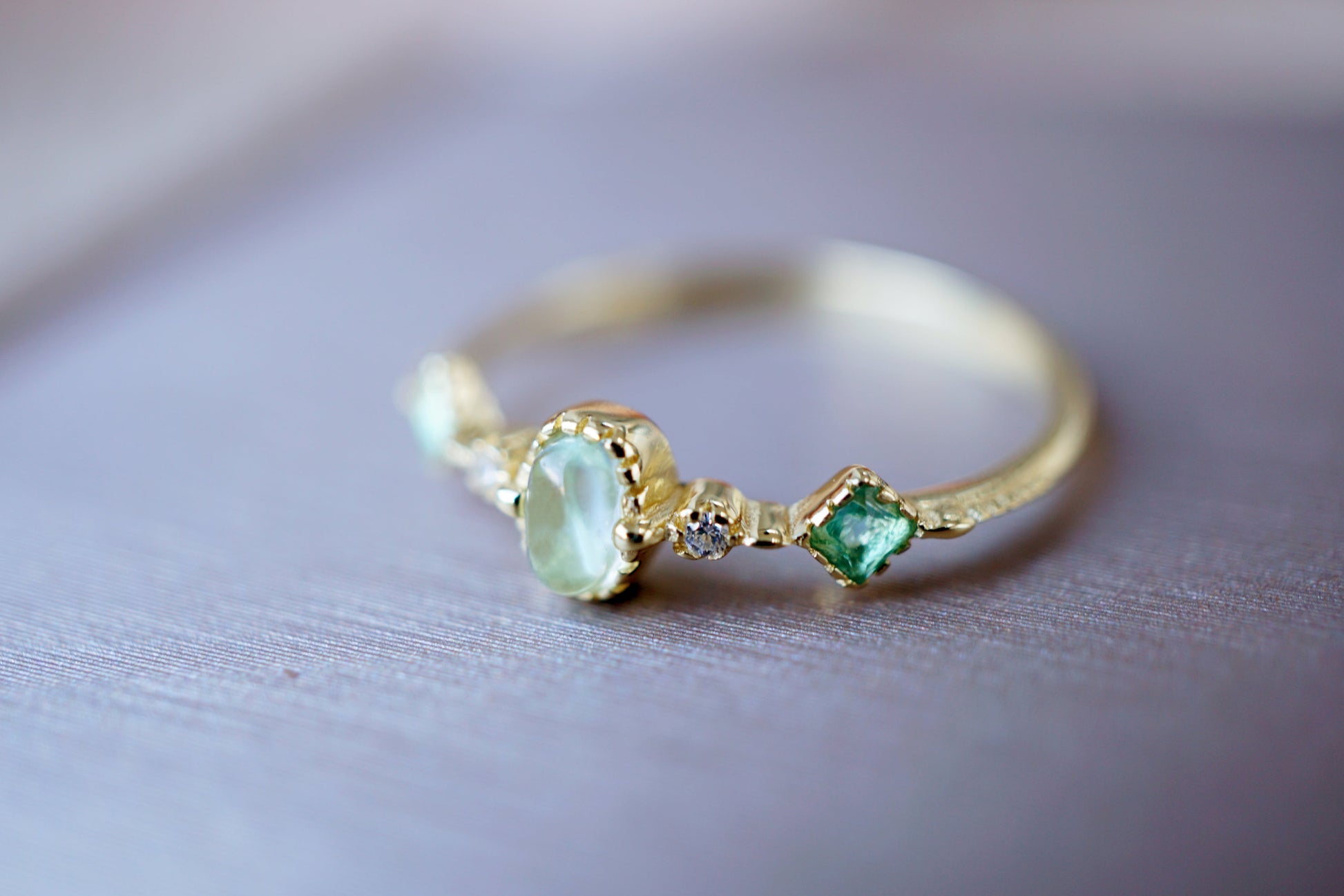 Gold ring with green gemstones on a light background