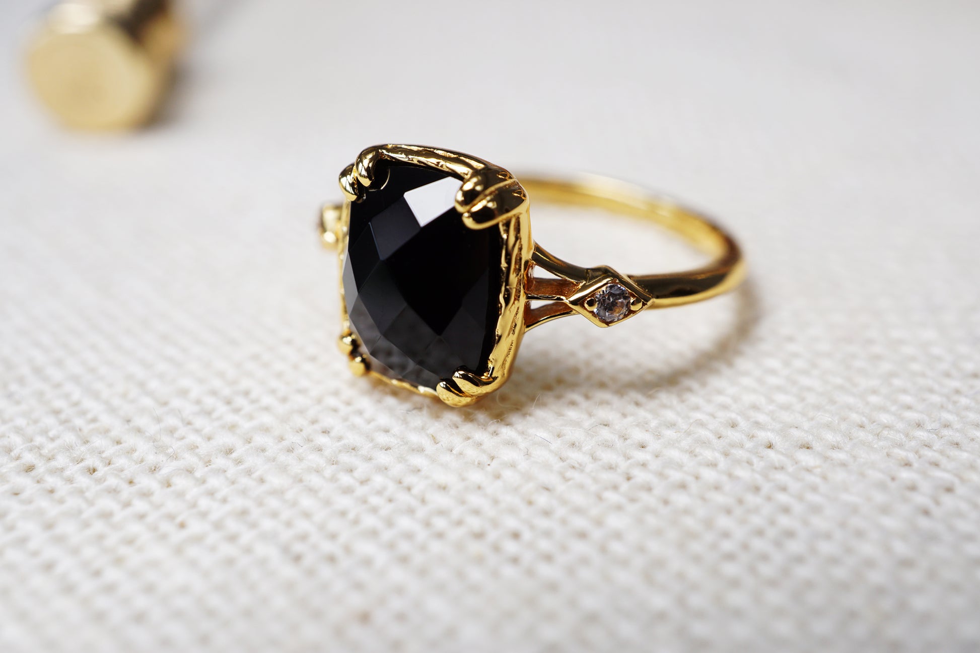 Gold ring with a black gemstone on a textured white background