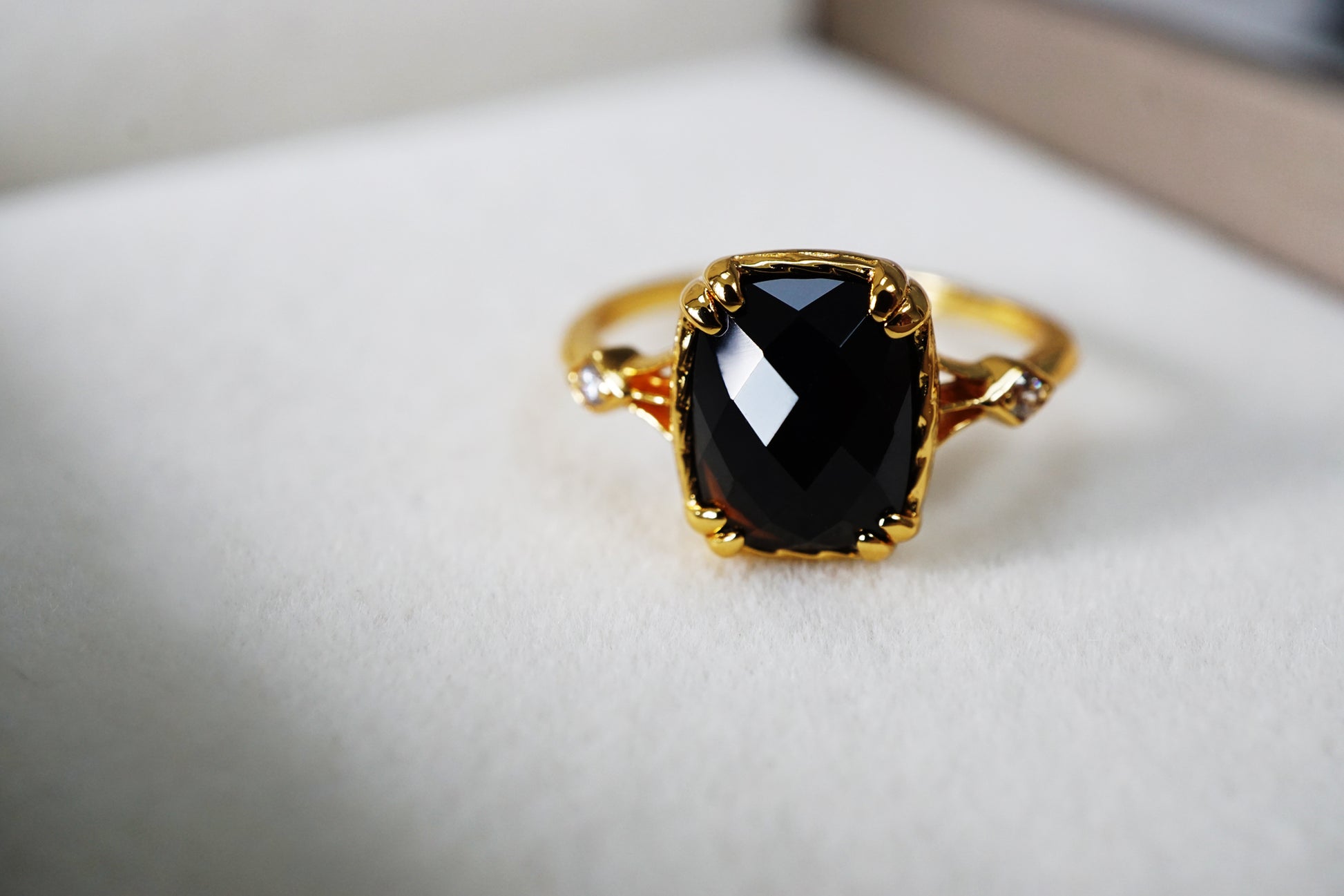 Gold ring with a black gemstone on a white cushion