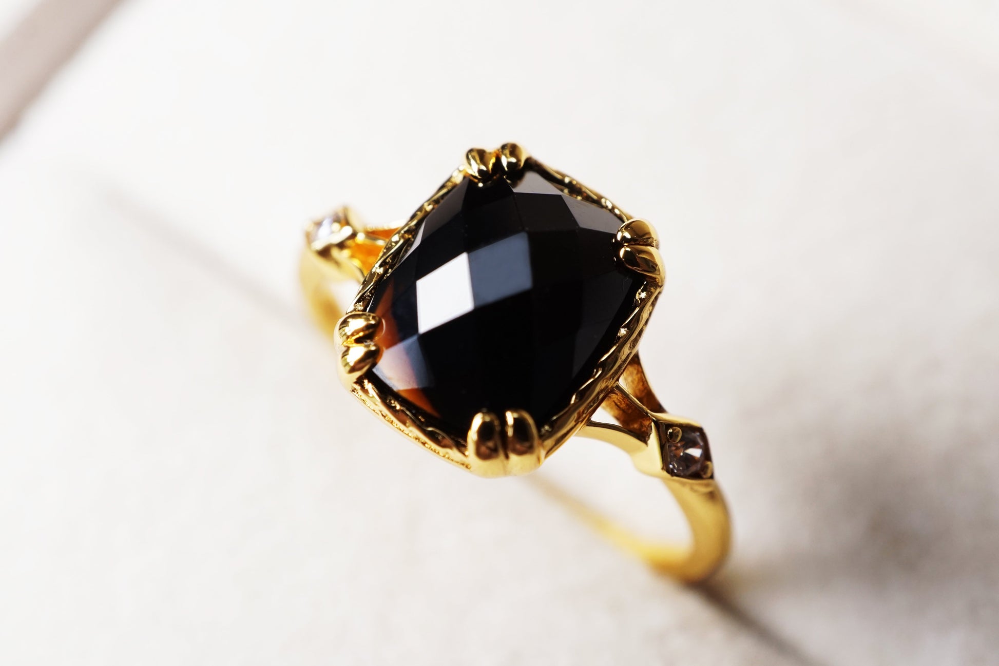 Gold ring with a large black gemstone on a light background