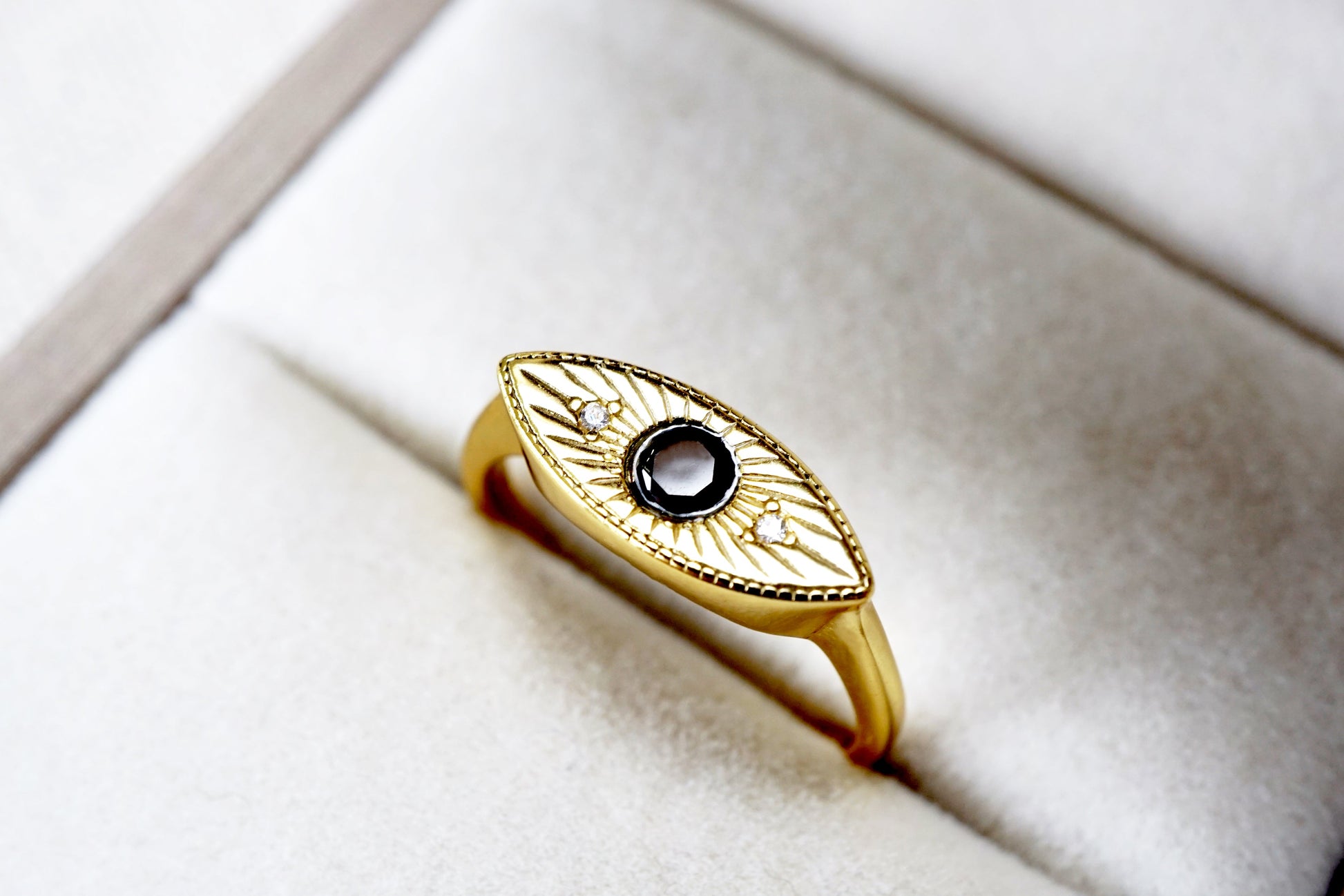 Gold ring with a black gemstone on a white cushion