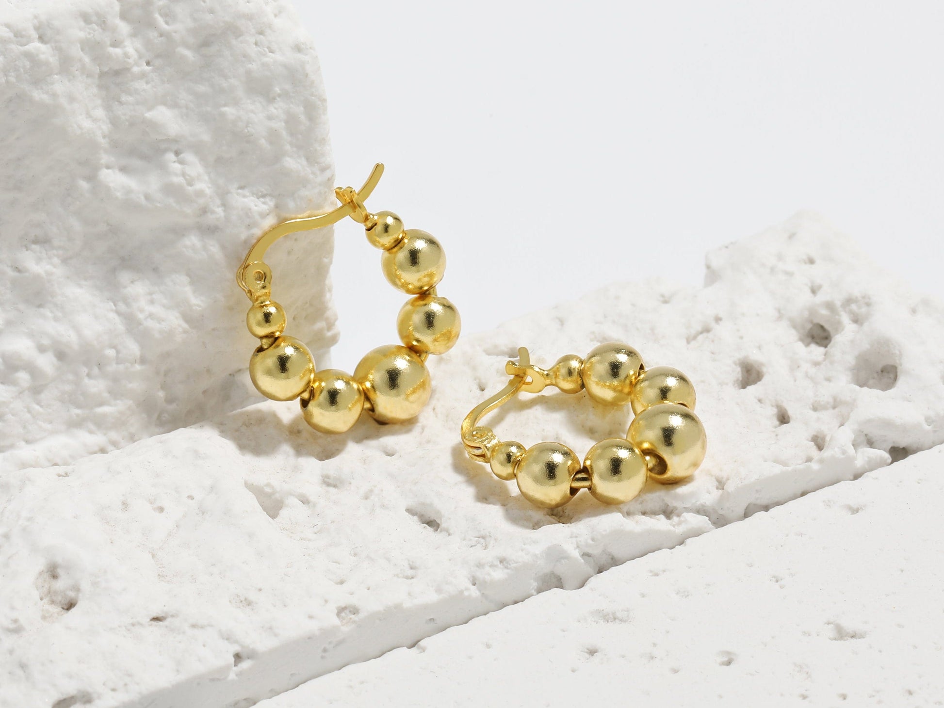 Gold hoop earrings on a textured white surface