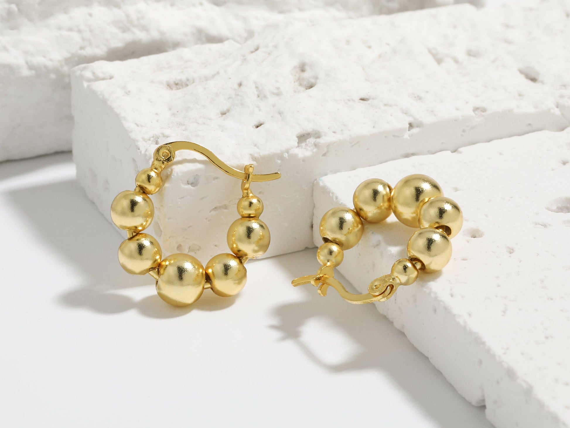 Gold hoop earrings on a textured white surface