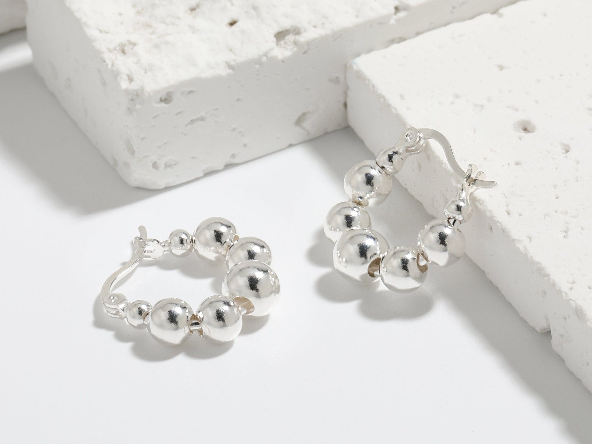 Silver hoop earrings on a textured white surface