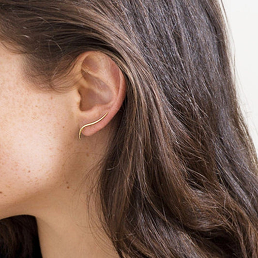 Close-up of a person wearing a thin hoop earring with a plain background