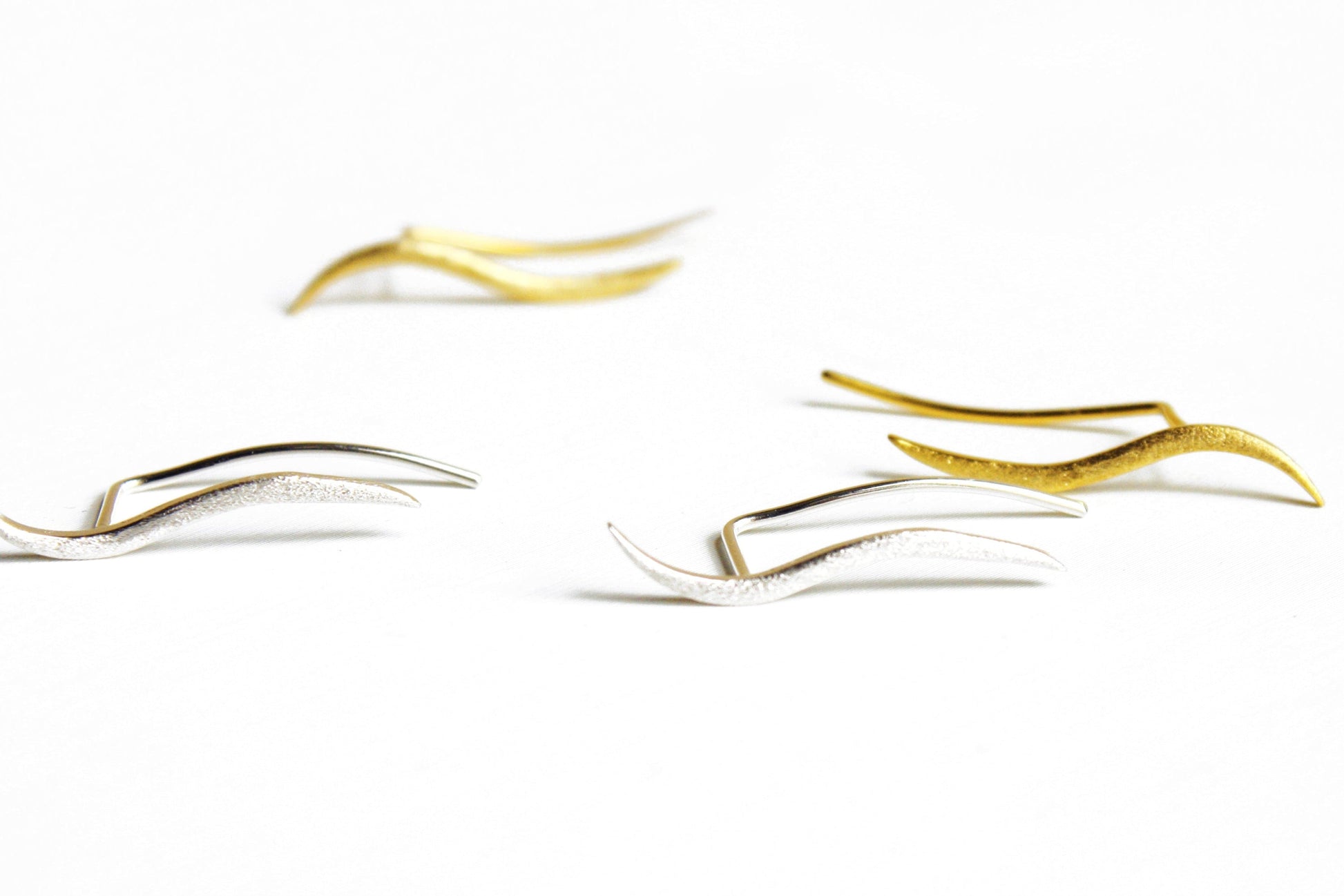 Gold and silver earrings on a white background
