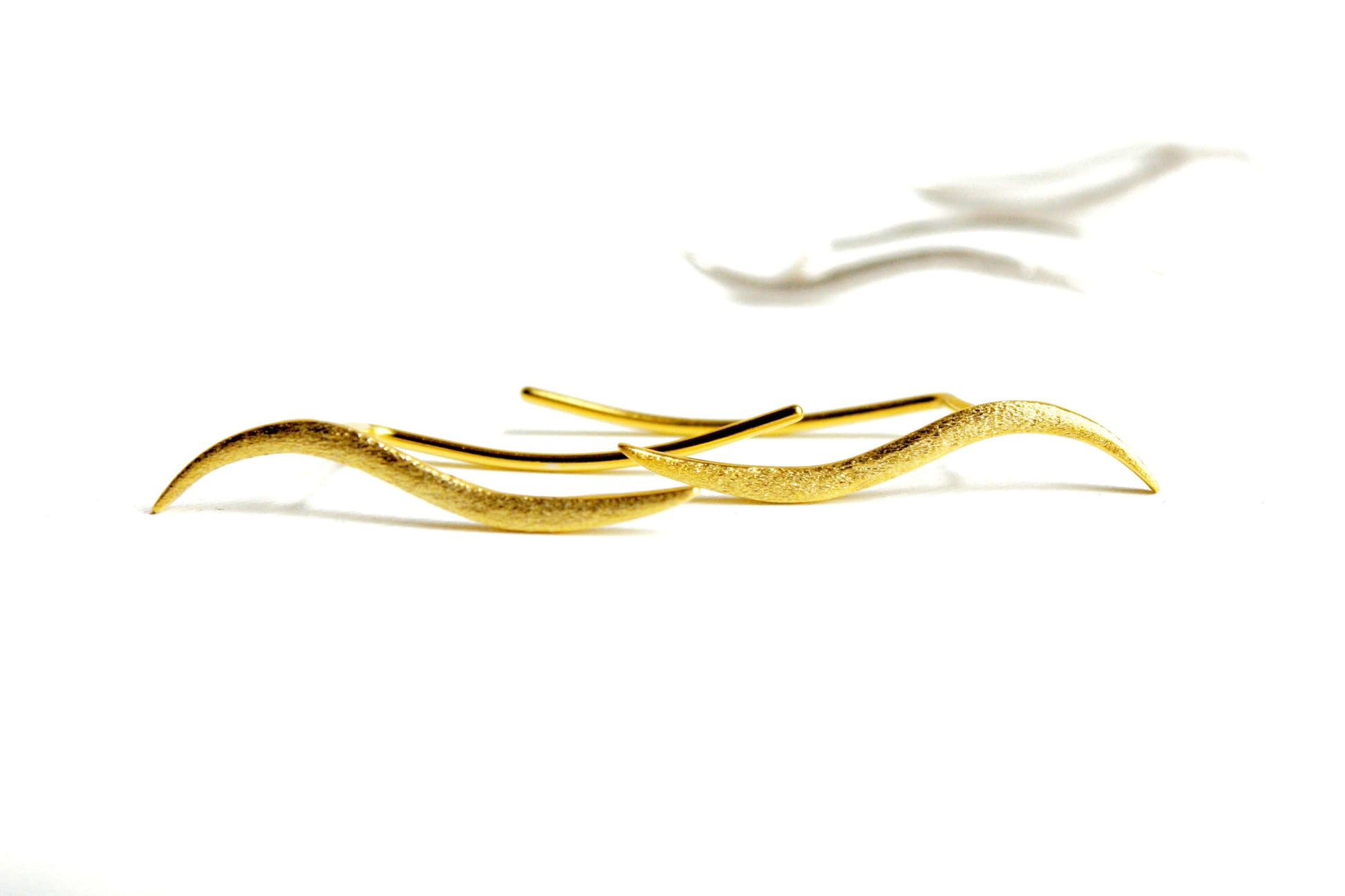 Gold bracelet with wavy design on a white background