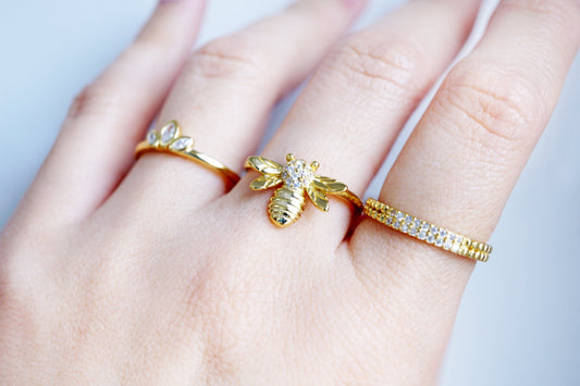 Hand wearing three gold rings on a light gray background