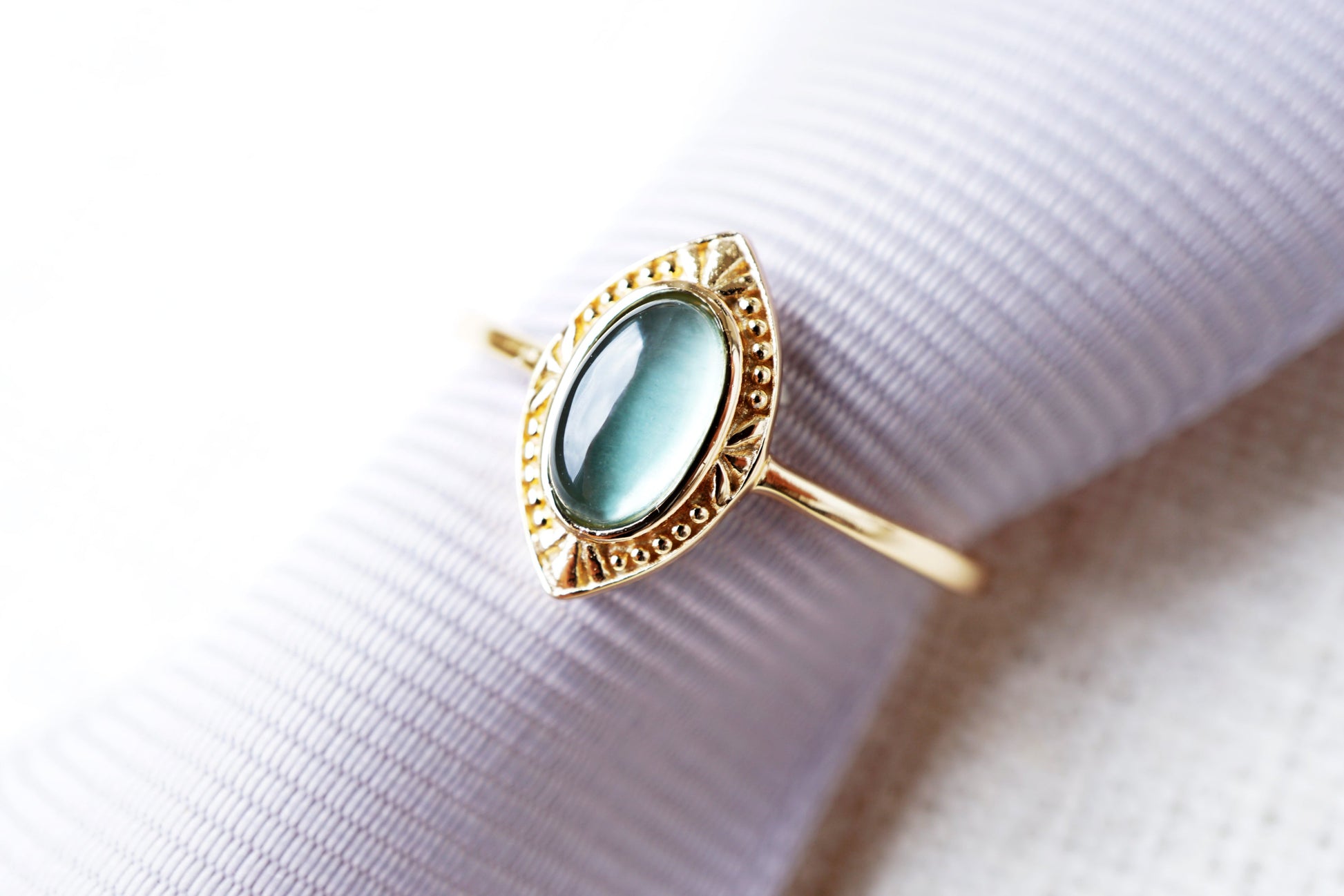 Gold ring with a green gemstone on a white fabric background