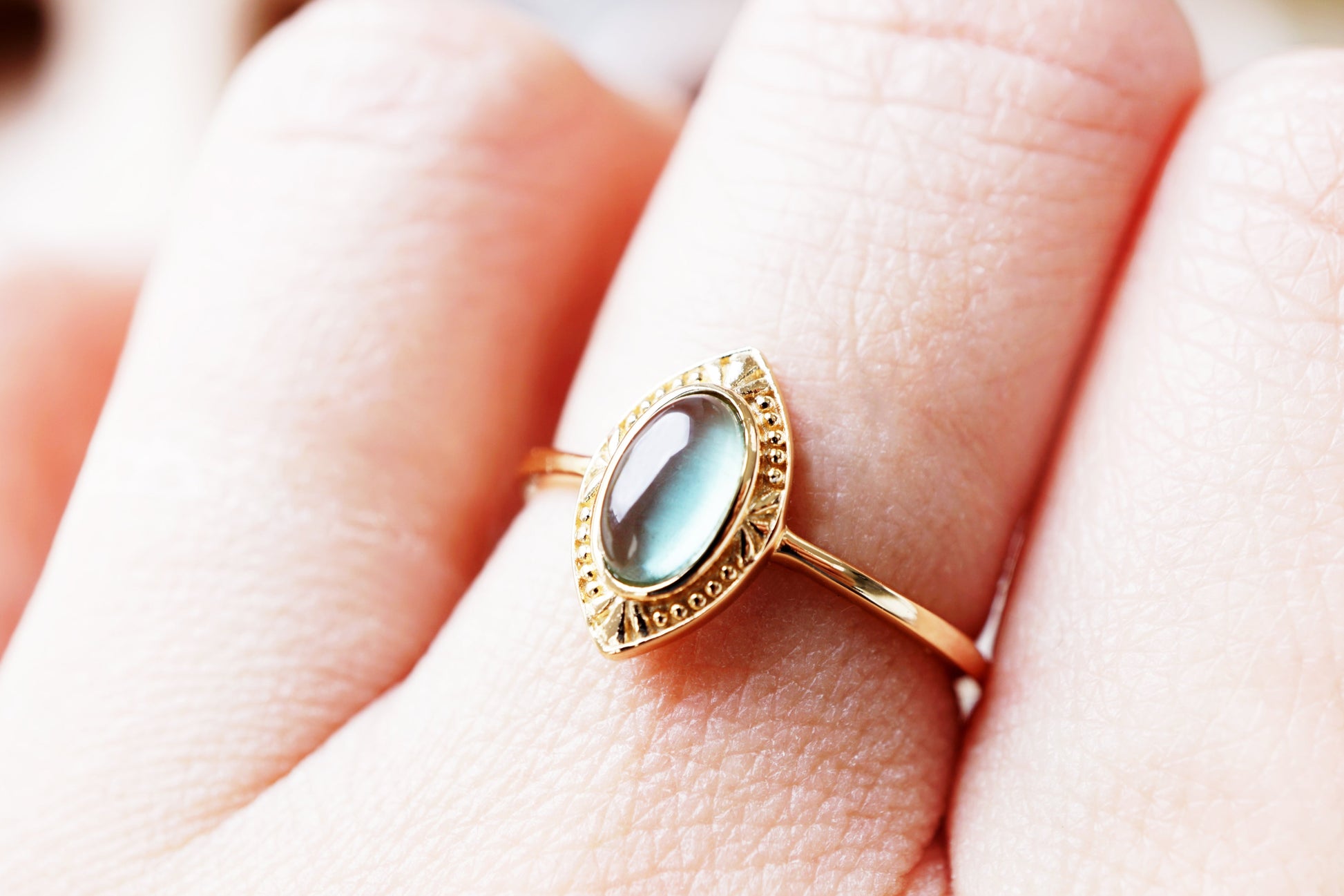 Gold ring with a gemstone on a person's finger