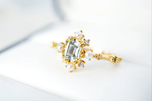 Gold ring with a central gemstone and smaller stones on a light background