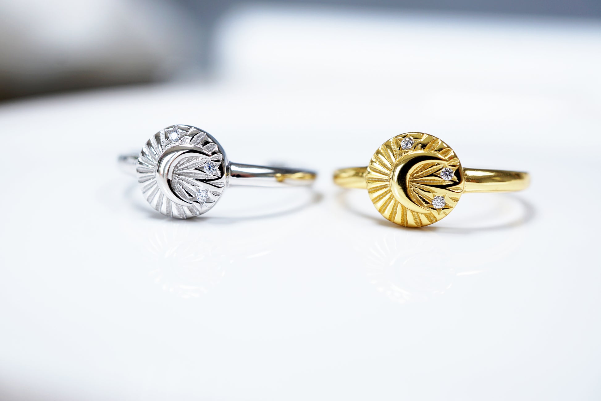Two rings, one silver and one gold, on a light background