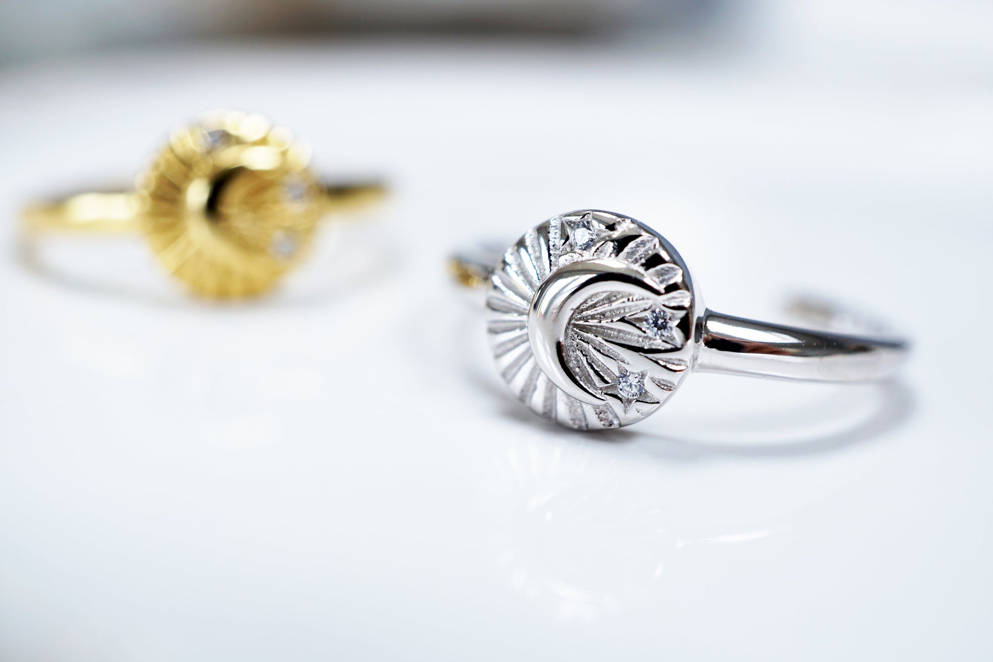 Two rings, one gold and one silver, on a light background