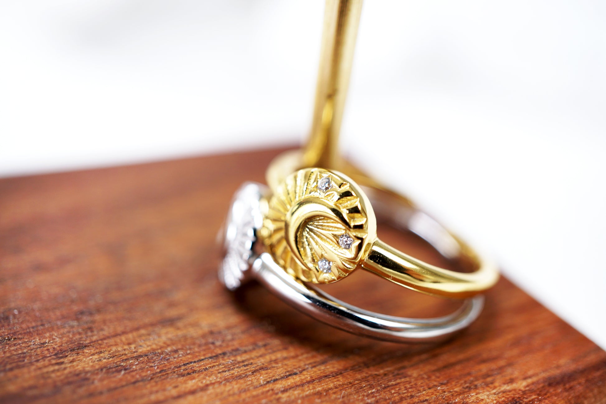 Gold and silver ring with diamond accents on a wooden surface