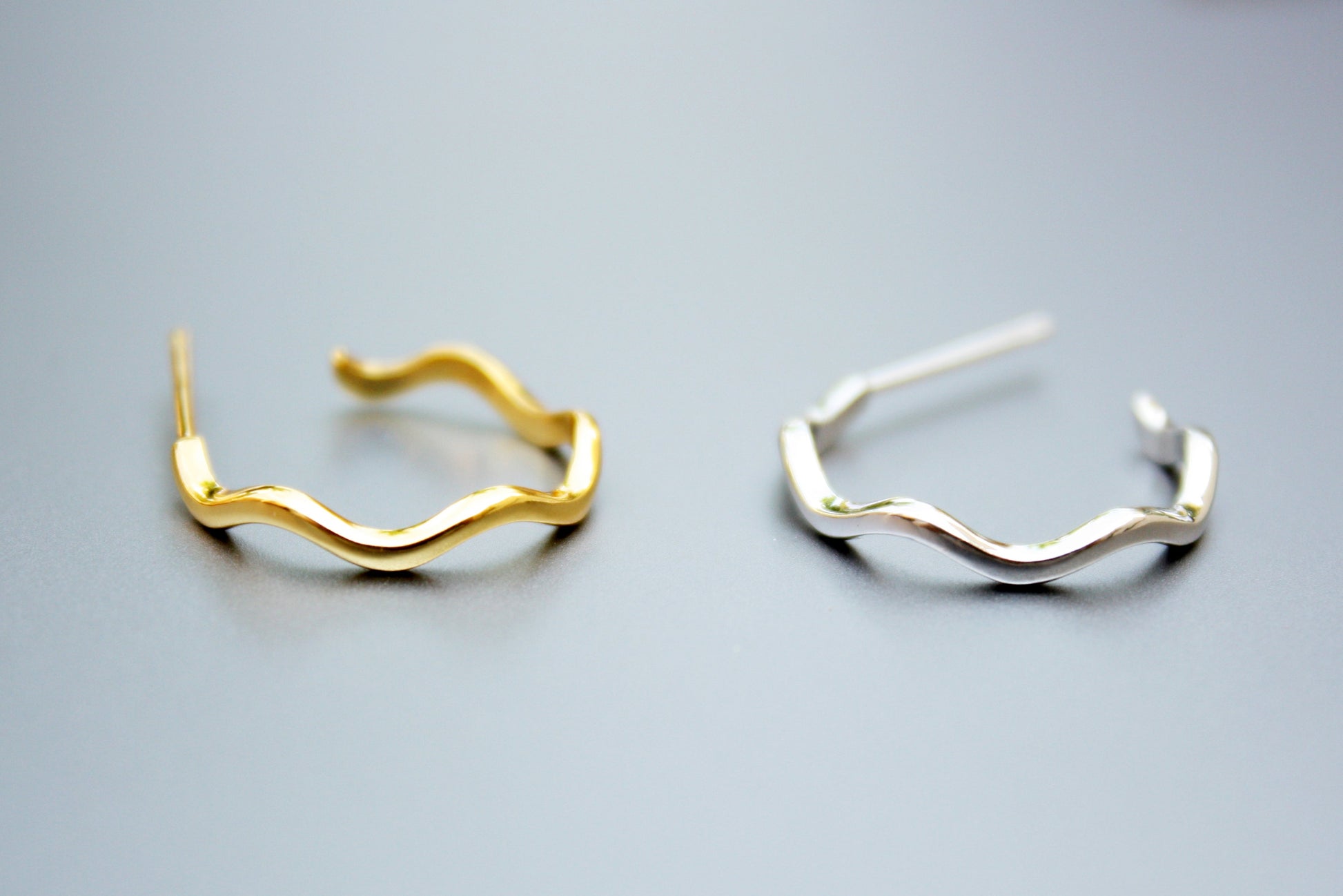 Gold and silver hoop earrings on a gray background