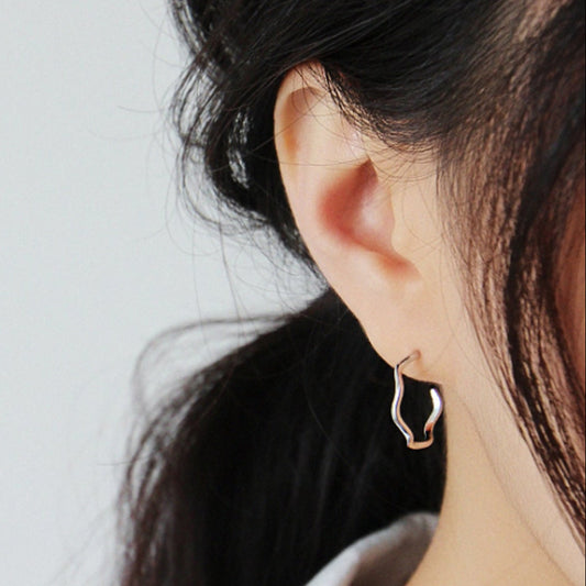 Close-up of a person wearing a hoop earring with a plain background