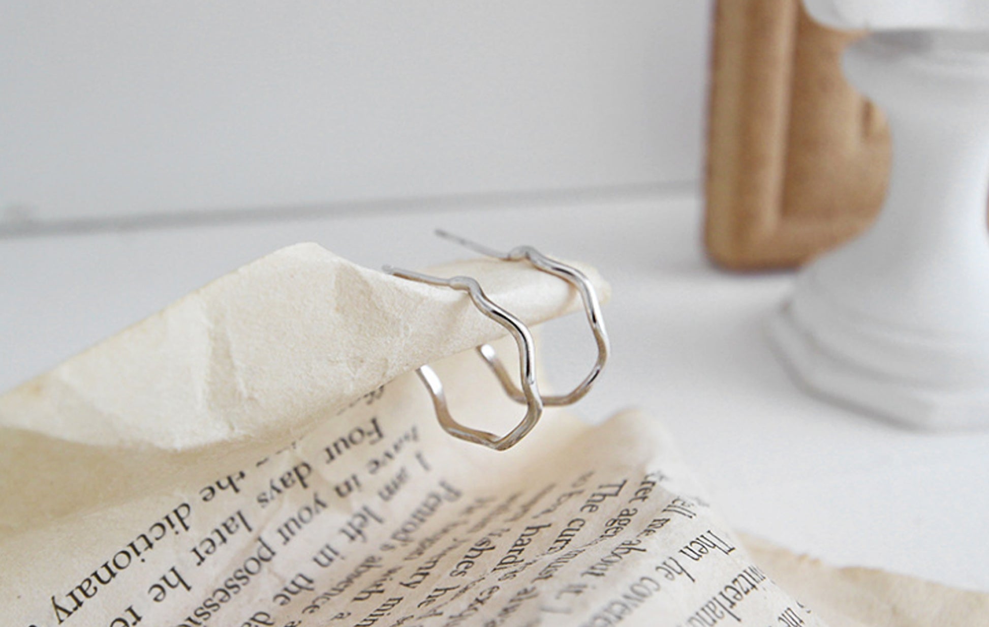 Silver hoop earrings on a piece of paper with a blurred background