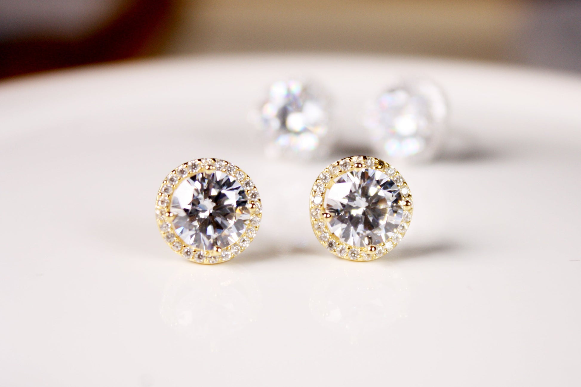 Gold earrings with clear gemstones on a white surface