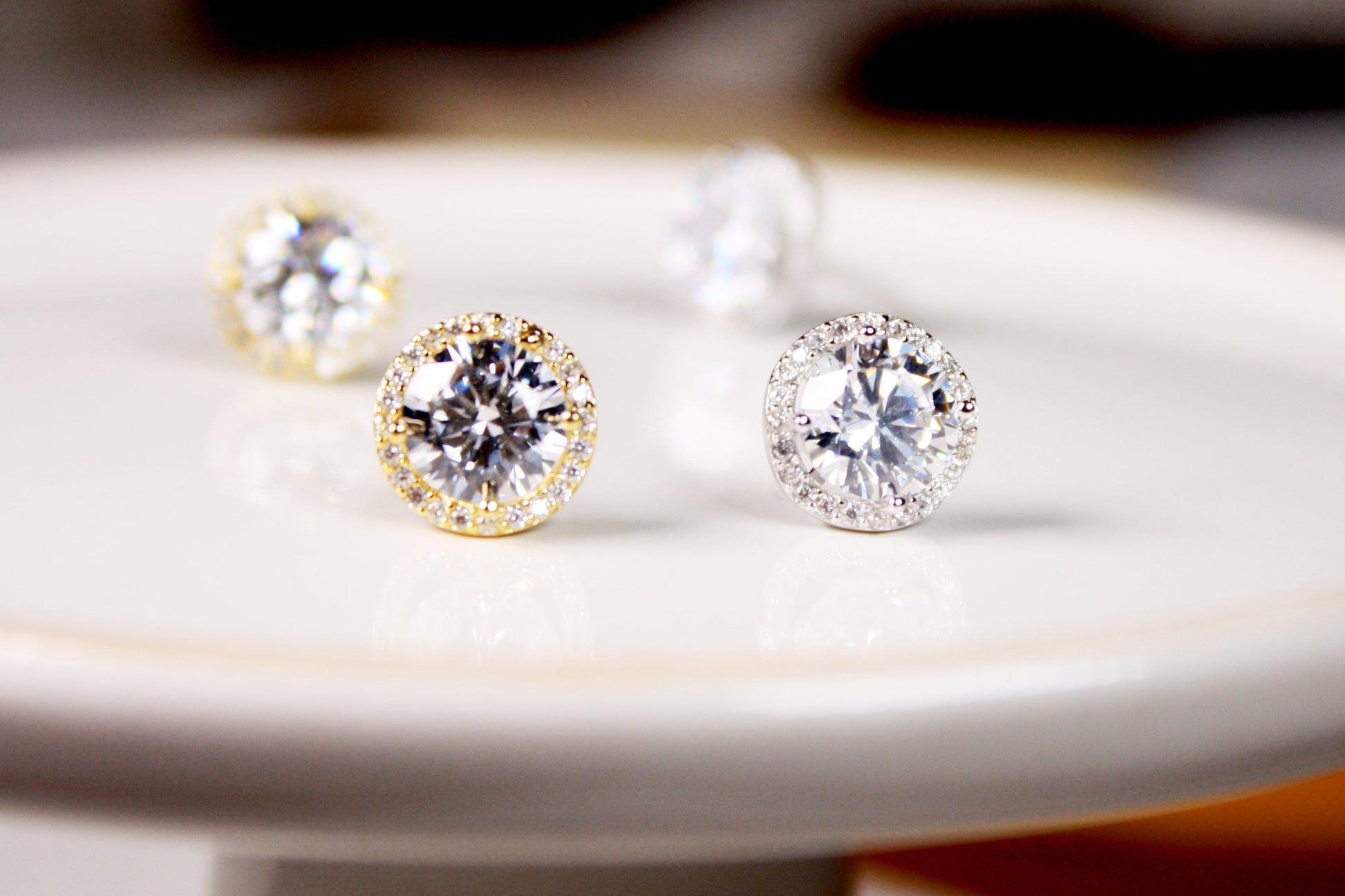 Diamond stud earrings on a white plate with a blurred background