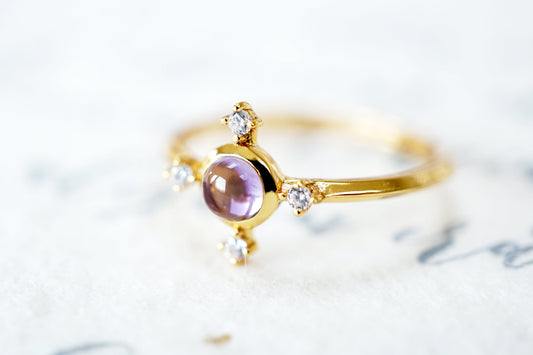 Gold ring with a purple gemstone on a light background