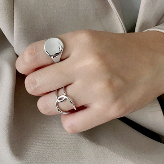 Close-up of a hand wearing two silver rings on beige fabric