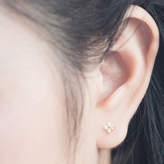Close-up of an ear wearing a star-shaped earring with additional earrings on a light blue background.