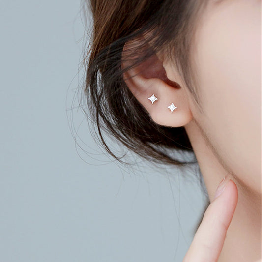 Close-up of a person wearing star-shaped earrings against a light gray background