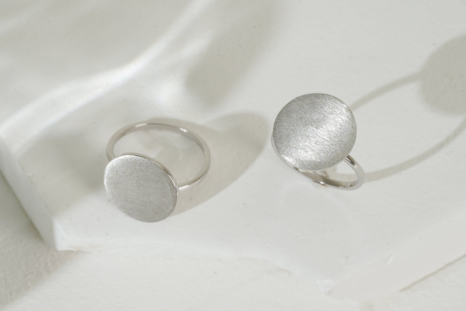 Two silver rings on a white fabric background