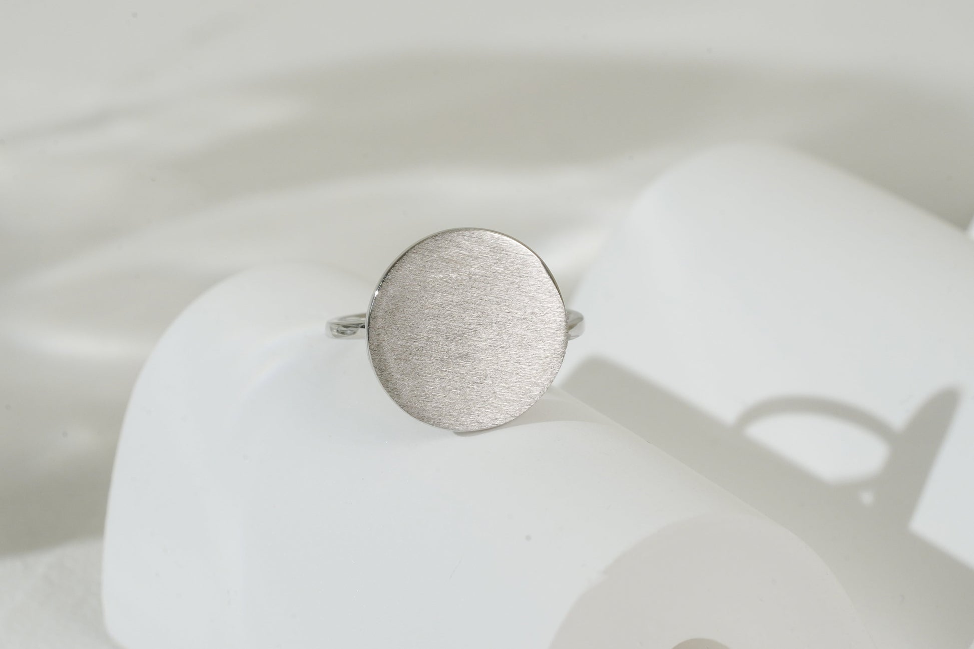 Silver ring on a white stand with a blurred background