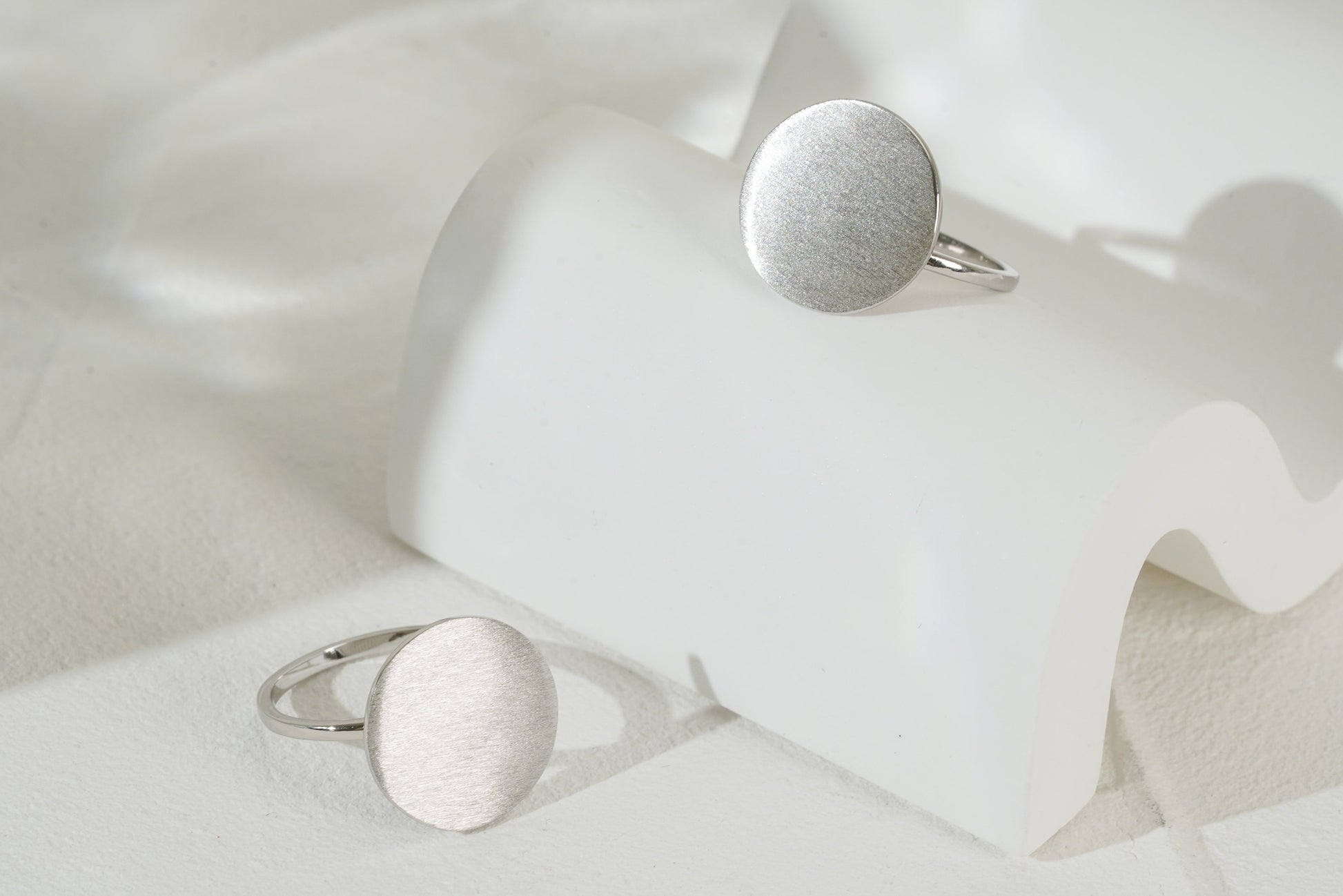 Two silver rings on a white fabric background