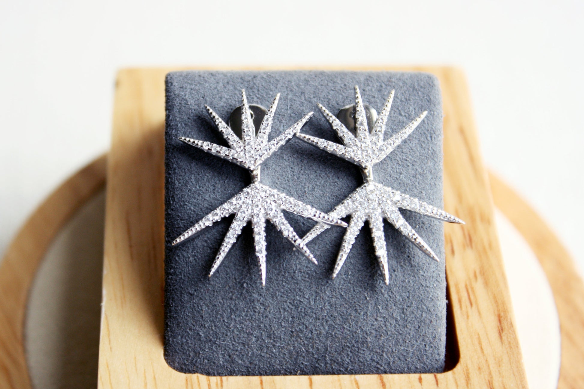 Star-shaped earrings on a dark gray square stone with a wooden base