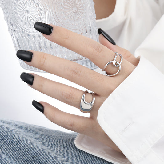 Hand wearing two silver rings with black nail polish on a white background