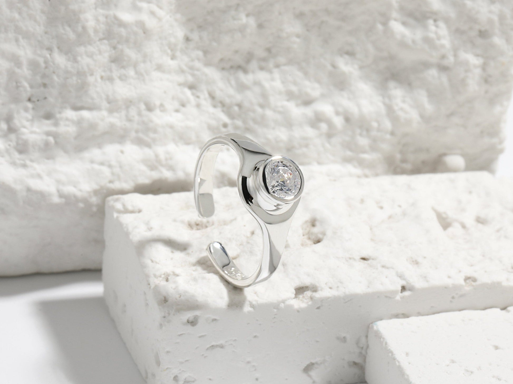 Silver ring with a diamond on a textured white surface