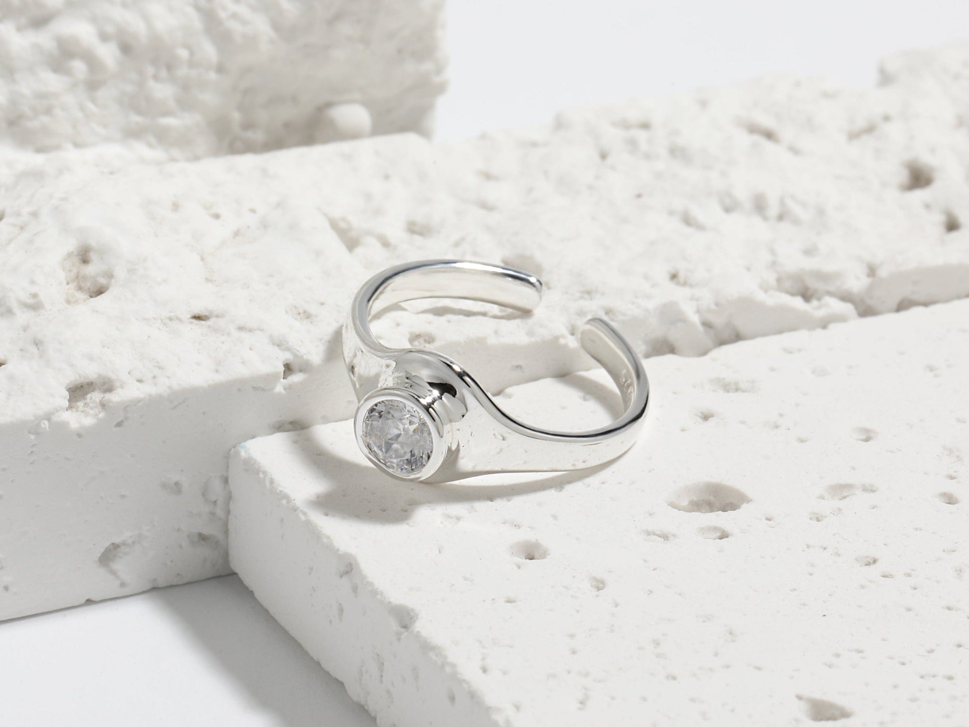 Silver ring with a gemstone on a light stone surface