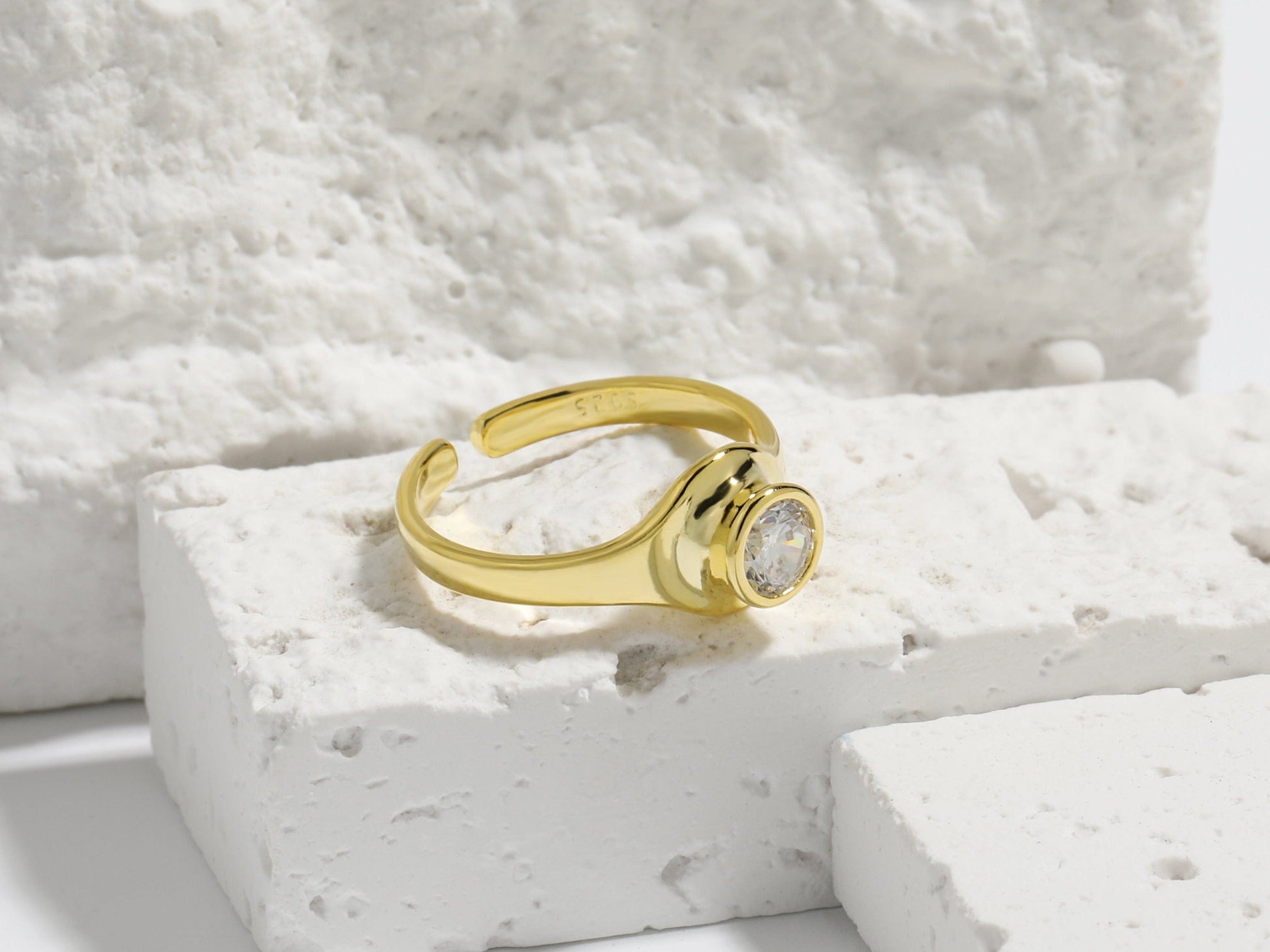 Gold ring with a gemstone on a textured white surface