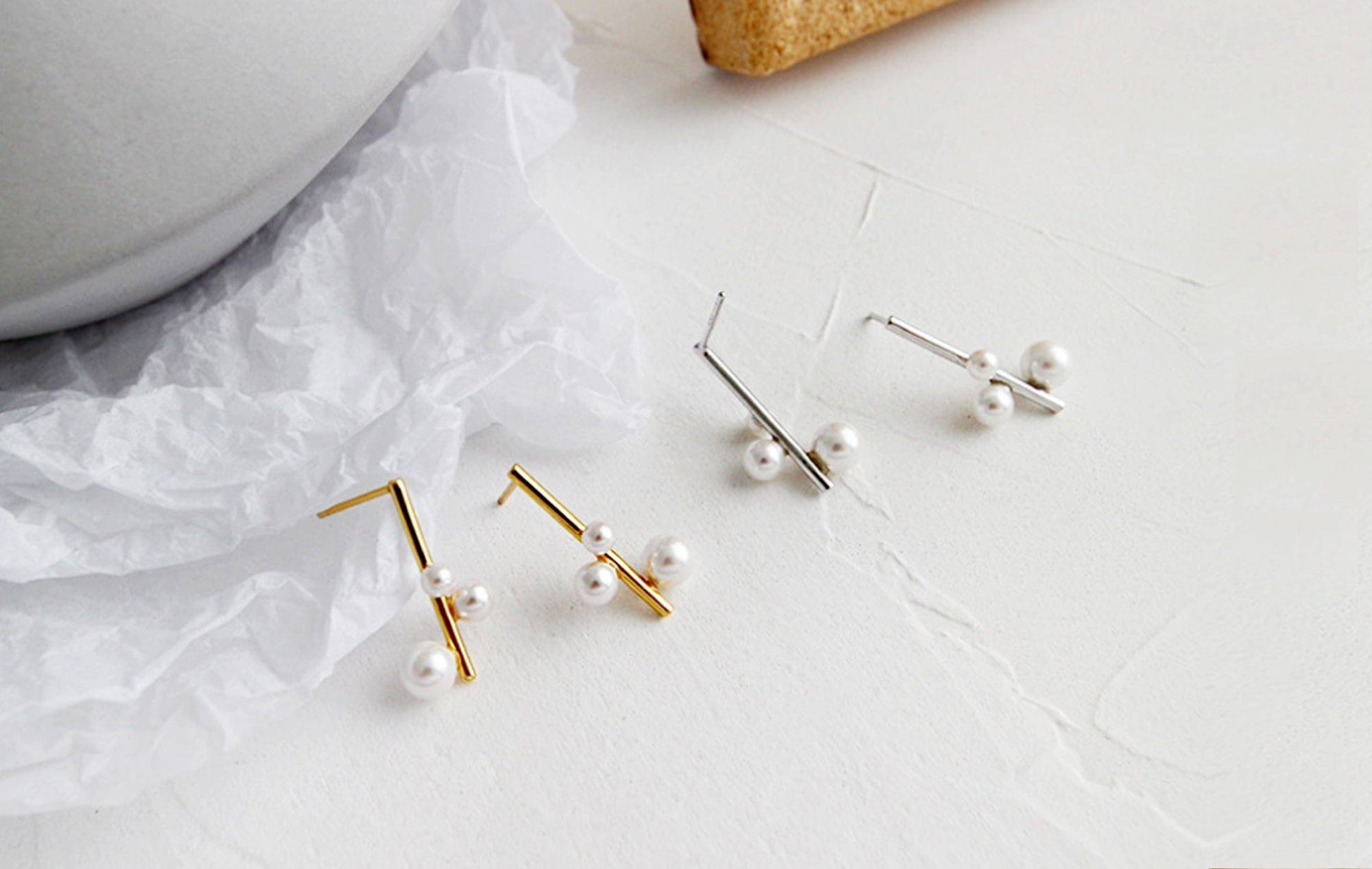 Gold and pearl earrings on a white surface