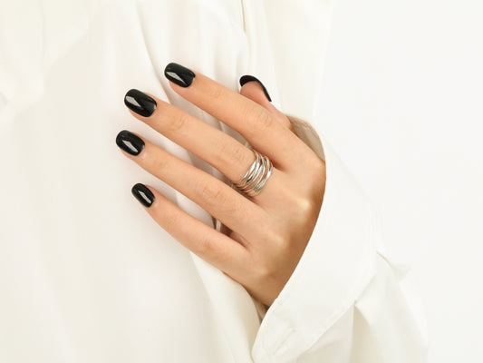 Hand with black nail polish and silver rings on a white background