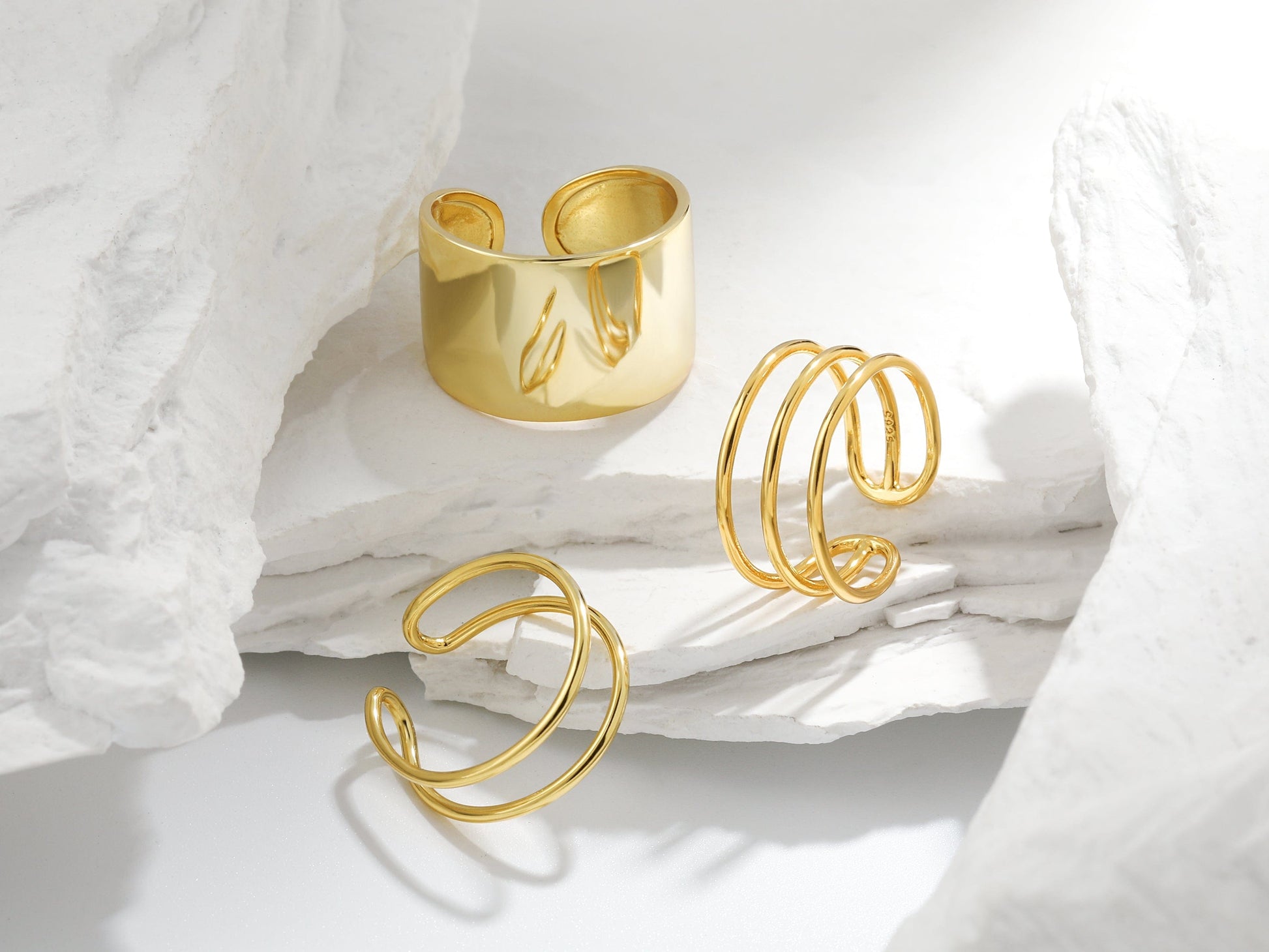 Gold open rings on a white fabric background