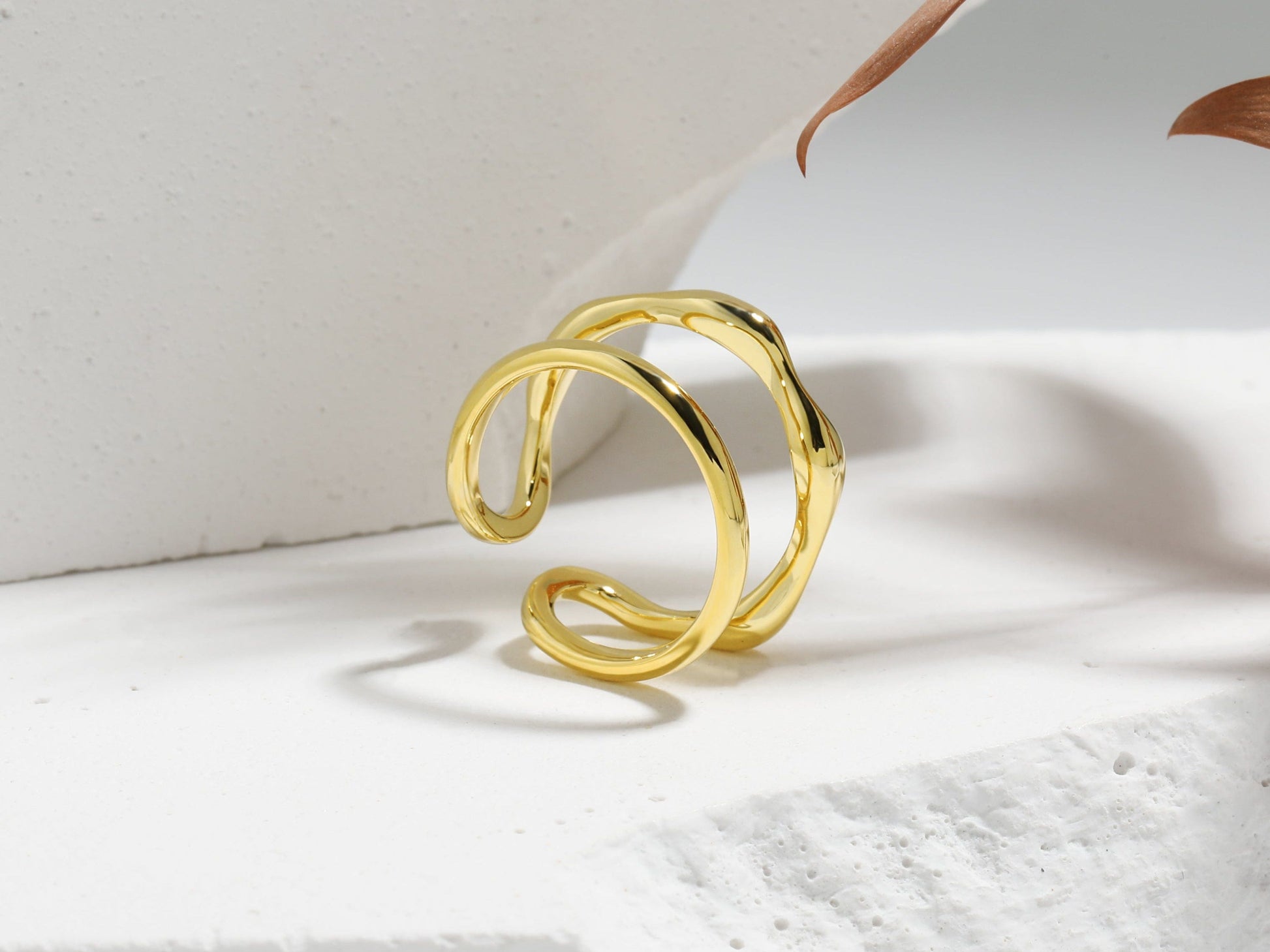 Gold ring on a white pedestal with a neutral background