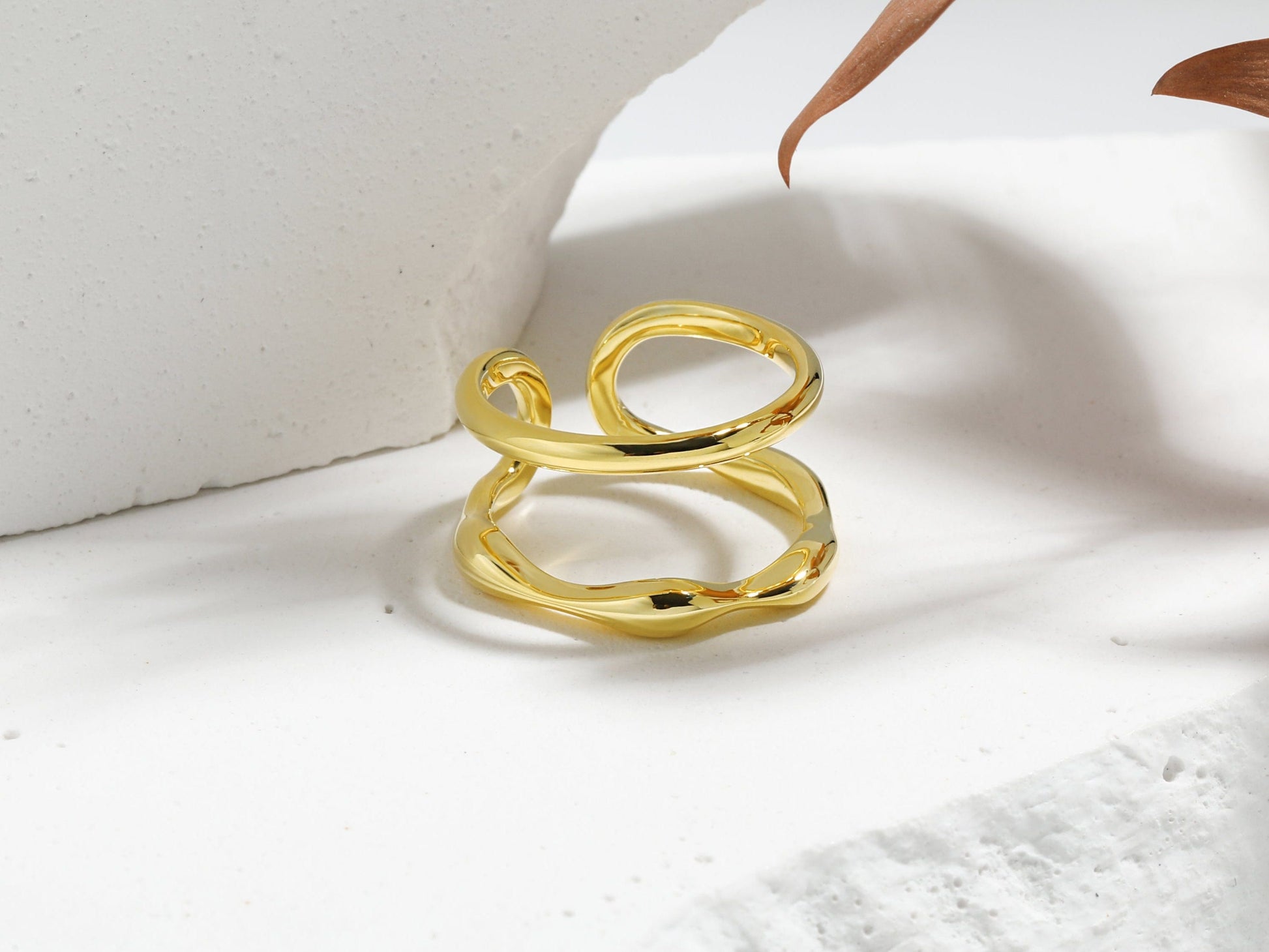 Gold ring on a white surface with a leaf
