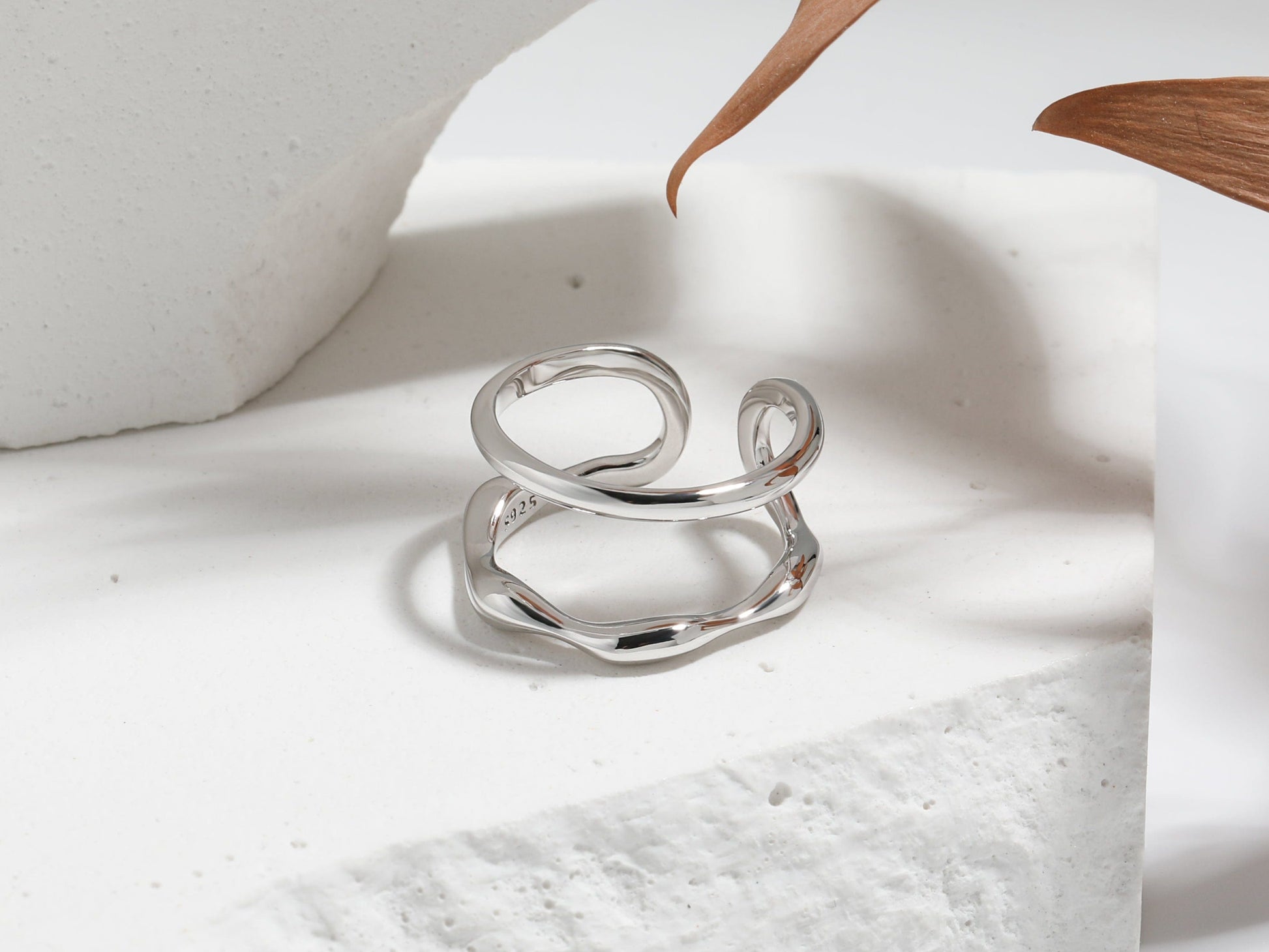 Silver ring on a white surface with a wooden object in the background