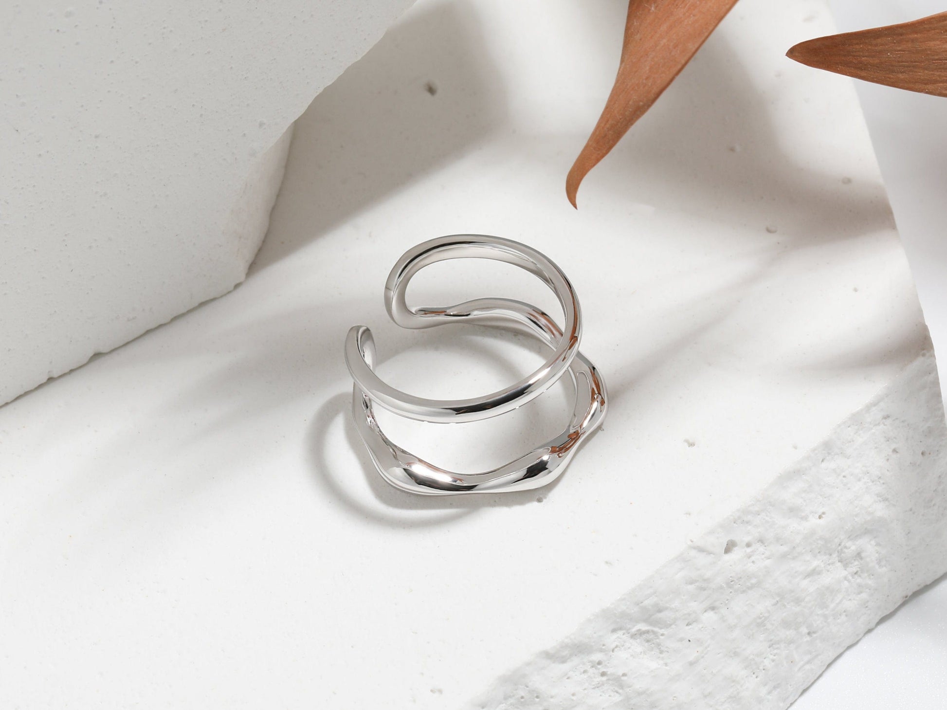 Silver ring on a white fabric surface with a wooden object in the background