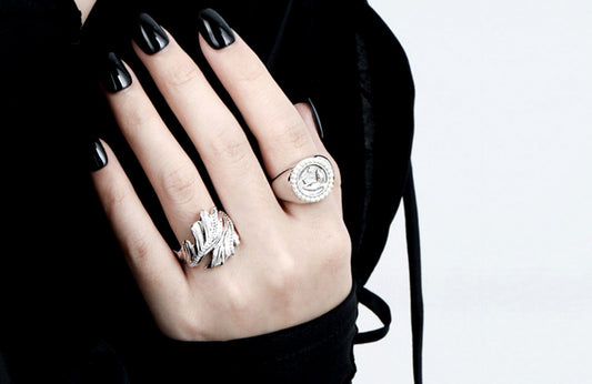 Hand wearing two silver rings with a black background