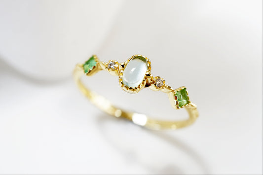 Gold ring with green gemstones on a white background