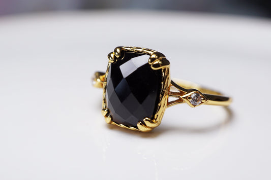 Gold ring with a large black gemstone on a white surface