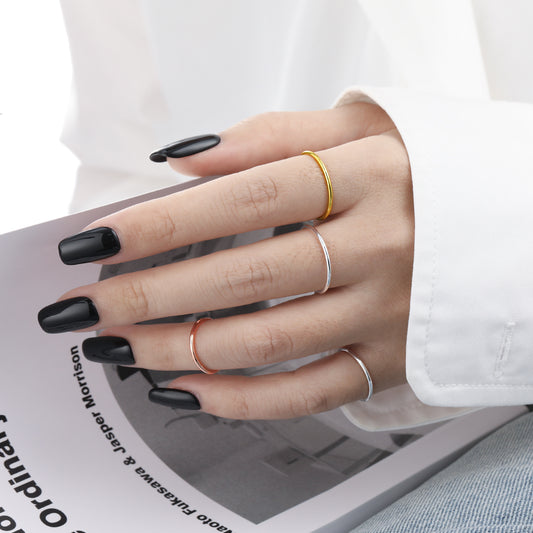 Hand with black nail polish wearing multiple rings on a magazine background