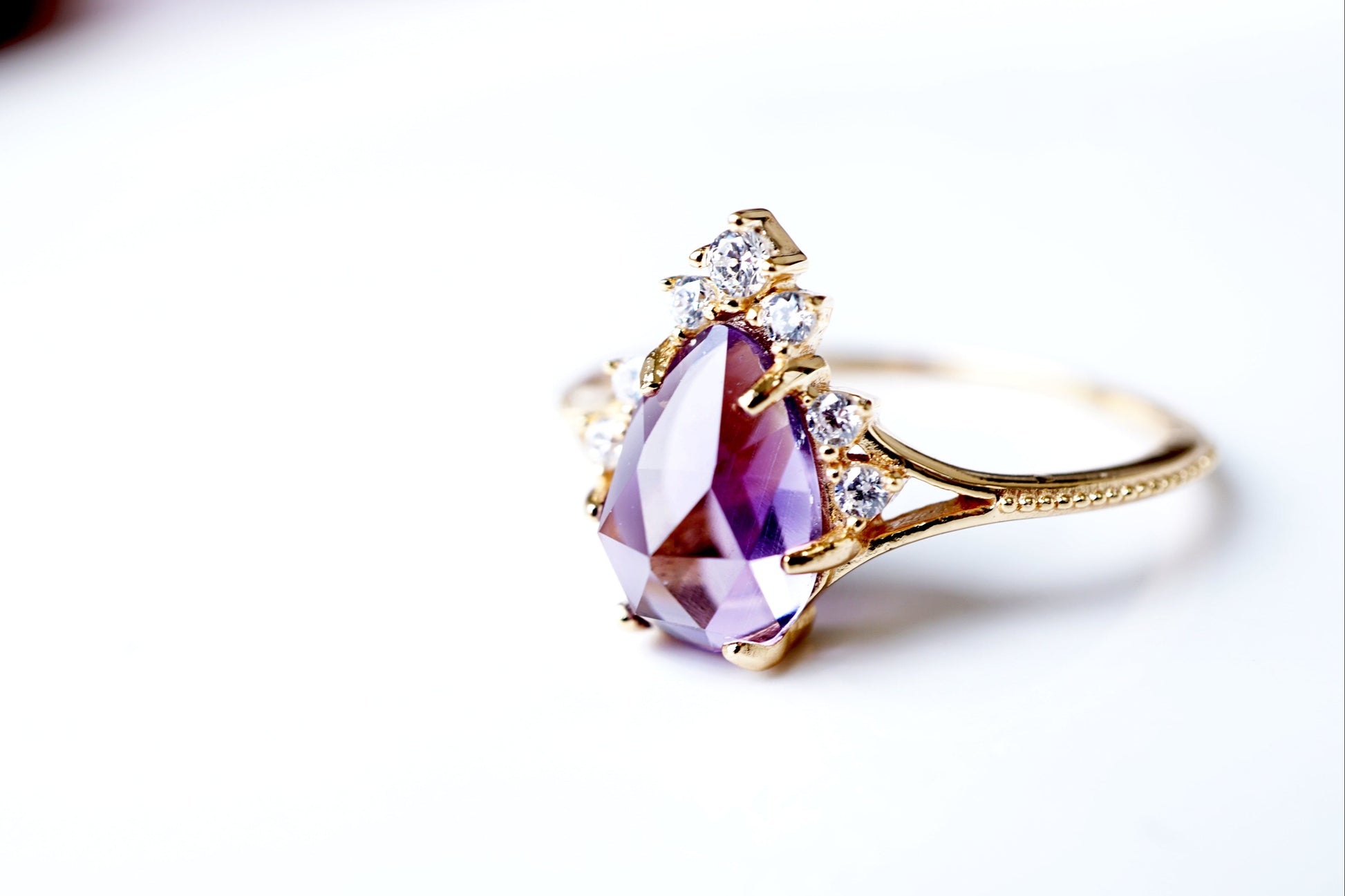 Gold ring with a purple gemstone on a white background