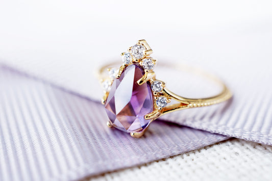 Gold ring with a purple gemstone on a white background