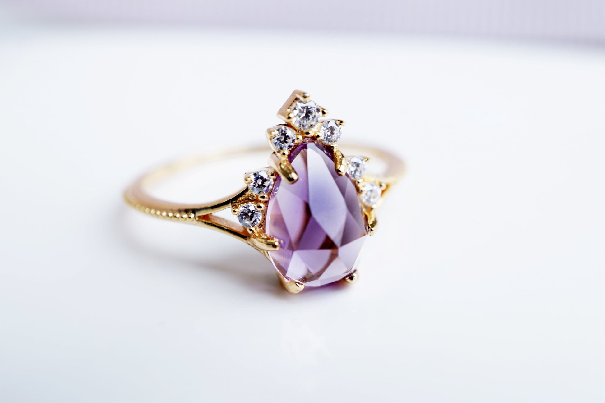 Gold ring with a pink gemstone on a light gray background